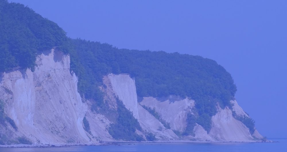 steep cliff overlooking water, blue overlay